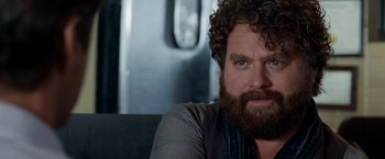 Movie still from “Due Date” (2010), directed by Todd Phillips – A man with a beard sitting on a couch; Close Up shot, Over the shoulder angle