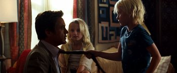 Movie still from “Due Date” (2010), directed by Todd Phillips – A man and two young girls holding onto a tie; Medium shot, Over the shoulder angle