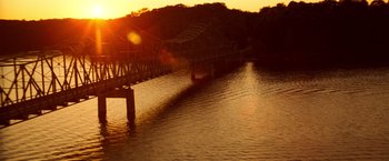 Movie still from “Due Date” (2010), directed by Todd Phillips – The sun is setting over a river with a bridge; Extreme Wide shot, High angle