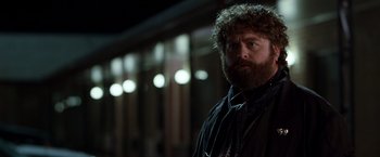 Movie still from “Due Date” (2010), directed by Todd Phillips – A man with a beard is standing in the dark; Close Up shot, Over the shoulder angle