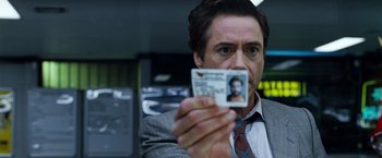 Movie still from “Due Date” (2010), directed by Todd Phillips – A person holding an id card; Close Up shot, Over the shoulder angle