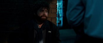 Movie still from “Due Date” (2010), directed by Todd Phillips – A man with a beard is sitting against a brick wall; Close Up shot, Over the shoulder angle