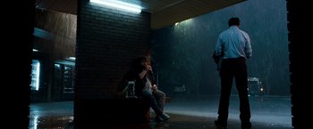 Movie still from “Due Date” (2010), directed by Todd Phillips – A woman sitting on a bench in the rain with a dog; Wide shot, Low angle