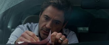 Movie still from “Due Date” (2010), directed by Todd Phillips – A person in a car holding a paper; Close Up shot, High angle