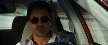 Movie still from “Due Date” (2010), directed by Todd Phillips – A person in a car wearing sunglasses; Close Up shot, Over the shoulder angle