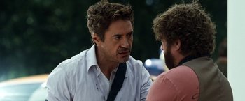 Movie still from “Due Date” (2010), directed by Todd Phillips – A man in a white dress shirt is talking to another man in a black tie; Close Up shot, Over the shoulder angle
