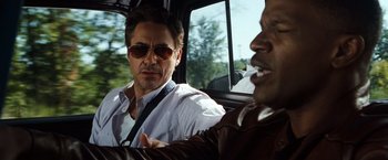 Movie still from “Due Date” (2010), directed by Todd Phillips – Two men are driving in a car and one of them is wearing sunglasses; Close Up shot, Over the shoulder angle