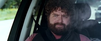Movie still from “Due Date” (2010), directed by Todd Phillips – A man with a beard is sitting in a car; Close Up shot, Over the shoulder angle