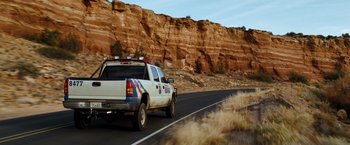 Movie still from “Due Date” (2010), directed by Todd Phillips – A truck driving down a road next to a mountain; Wide shot, Low angle