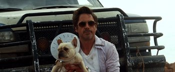 Movie still from “Due Date” (2010), directed by Todd Phillips – A man holding a small dog in his arms; Close Up shot, Low angle