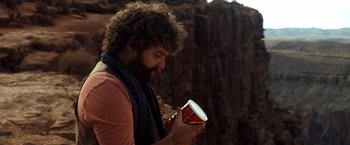Movie still from “Due Date” (2010), directed by Todd Phillips – A man holding a can of soda in his hands; Medium shot, Low angle