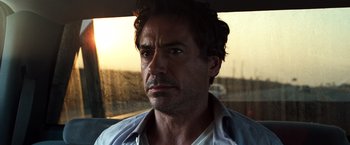 Movie still from “Due Date” (2010), directed by Todd Phillips – A person with a car in the background; Close Up shot, Over the shoulder angle