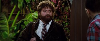 Movie still from “Due Date” (2010), directed by Todd Phillips – A man with a beard wearing a suit and tie; Medium shot, Over the shoulder angle