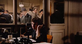 Movie still from “The Sting” (1973), directed by George Roy Hill – A woman sitting at a table in front of a microphone; Medium shot, High angle