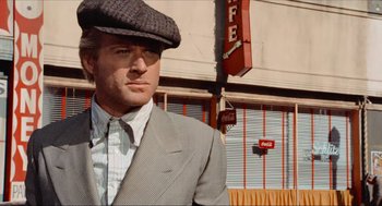 Movie still from “The Sting” (1973), directed by George Roy Hill – A man in a suit and hat standing in front of a building; Close Up shot, Low angle