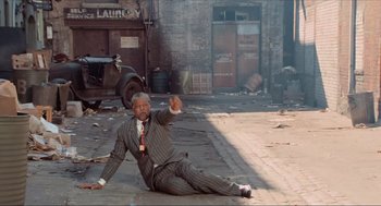 Movie still from “The Sting” (1973), directed by George Roy Hill – A man in a suit is sitting on the ground; Wide shot, High angle