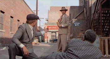 Movie still from “The Sting” (1973), directed by George Roy Hill – A man in a suit and a hat standing in the street; Wide shot, Over the shoulder angle
