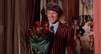 Movie still from “The Sting” (1973), directed by George Roy Hill – A man holding a bouquet of roses in a suit and hat; Medium shot, High angle