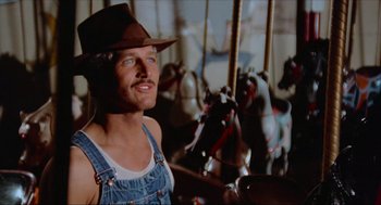 Movie still from “The Sting” (1973), directed by George Roy Hill – A man wearing a cowboy hat standing in front of a merry go round; Close Up shot, Low angle