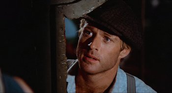 Movie still from “The Sting” (1973), directed by George Roy Hill – A person wearing a hat and looking to his left; Close Up shot, Over the shoulder angle