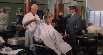Movie still from “The Sting” (1973), directed by George Roy Hill – A man getting his hair cut in a barber shop; Medium shot, Over the shoulder angle