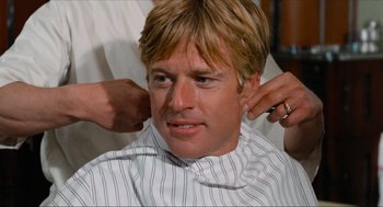 Movie still from “The Sting” (1973), directed by George Roy Hill – A man with blonde hair is getting his hair combed; Close Up shot, Over the shoulder angle