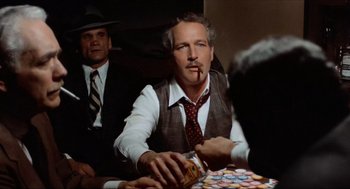 Movie still from “The Sting” (1973), directed by George Roy Hill – A man sitting at a table and smoking a cigarette; Medium shot, Over the shoulder angle