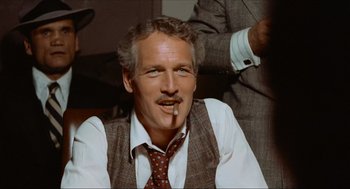 Movie still from “The Sting” (1973), directed by George Roy Hill – A person wearing a tie smoking a cigarette; Close Up shot, Over the shoulder angle