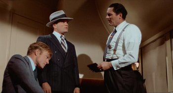 Movie still from “The Sting” (1973), directed by George Roy Hill – Two men and a woman wearing suits and hats; Medium shot, Over the shoulder angle