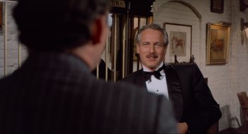 Movie still from “The Sting” (1973), directed by George Roy Hill – A man in a tuxedo is looking at himself in the mirror; Medium shot, Over the shoulder angle