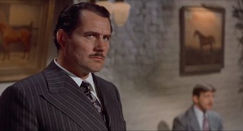 Movie still from “The Sting” (1973), directed by George Roy Hill – A man in a suit with a mustache; Close Up shot, Low angle