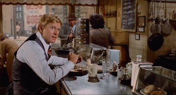 Movie still from “The Sting” (1973), directed by George Roy Hill – A man sitting at a counter in a restaurant; Medium shot, Over the shoulder angle
