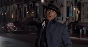 Movie still from “The Sting” (1973), directed by George Roy Hill – A man wearing a suit and a hat standing in the dark; Close Up shot, Over the shoulder angle