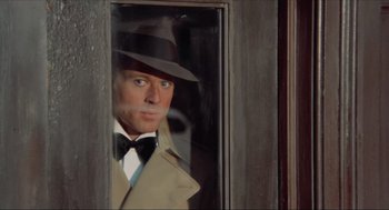 Movie still from “The Sting” (1973), directed by George Roy Hill – A man wearing a hat and a coat looking out of a window; Close Up shot, Over the shoulder angle