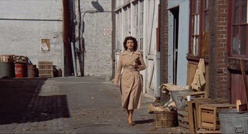 Movie still from “The Sting” (1973), directed by George Roy Hill – A woman walking down the street wearing a trench coat; Wide shot, High angle