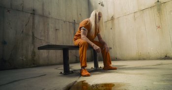 Movie still from “The Suicide Squad” (2021), directed by James Gunn – A man sitting on top of a wooden bench; Wide shot, High angle