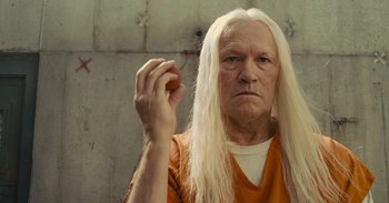 Movie still from “The Suicide Squad” (2021), directed by James Gunn – An old man with long white hair holding a donut; Close Up shot, Low angle