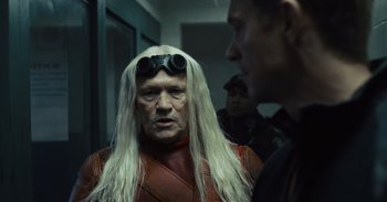 Movie still from “The Suicide Squad” (2021), directed by James Gunn – A man with long white hair wearing goggles and a wig; Close Up shot, Over the shoulder angle