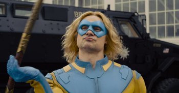 Movie still from “The Suicide Squad” (2021), directed by James Gunn – A man with blonde hair wearing a blue and yellow mask; Medium shot, Over the shoulder angle