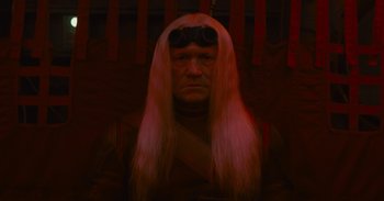 Movie still from “The Suicide Squad” (2021), directed by James Gunn – A man with long white hair wearing a wig; Close Up shot, Low angle