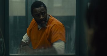 Movie still from “The Suicide Squad” (2021), directed by James Gunn – A man in an orange prison uniform sitting in front of a window; Medium shot, Over the shoulder angle