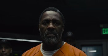 Movie still from “The Suicide Squad” (2021), directed by James Gunn – A man in an orange prison uniform stares at the camera; Close Up shot, Low angle