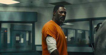 Movie still from “The Suicide Squad” (2021), directed by James Gunn – A man in an orange prison uniform standing in a room; Medium shot, Over the shoulder angle