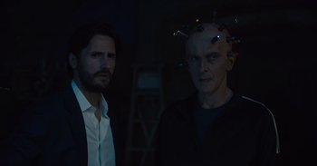 Movie still from “The Suicide Squad” (2021), directed by James Gunn – Two men standing next to each other in a dark room; Close Up shot, Over the shoulder angle