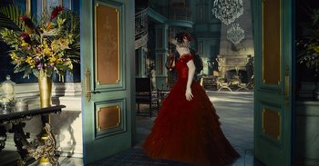 Movie still from “The Suicide Squad” (2021), directed by James Gunn – A woman in a red dress standing in front of an open door; Wide shot, Low angle
