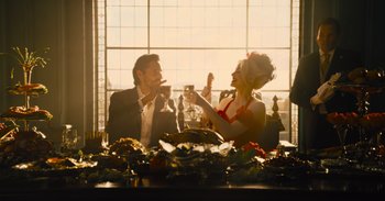 Movie still from “The Suicide Squad” (2021), directed by James Gunn – A man and a woman sitting at a dinner table; Medium shot, Over the shoulder angle