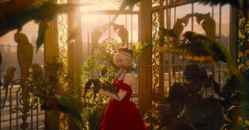 Movie still from “The Suicide Squad” (2021), directed by James Gunn – A woman in a red dress is holding a bird; Wide shot, Low angle