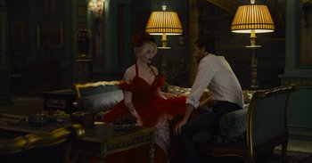 Movie still from “The Suicide Squad” (2021), directed by James Gunn – A woman in a red dress sitting next to a man in a white shirt; Wide shot, Over the shoulder angle