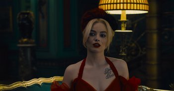 Movie still from “The Suicide Squad” (2021), directed by James Gunn – A woman in a red dress and a red hat; Close Up shot, Over the shoulder angle