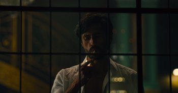 Movie still from “The Suicide Squad” (2021), directed by James Gunn – A man smoking a cigarette in front of a window; Close Up shot, Over the shoulder angle